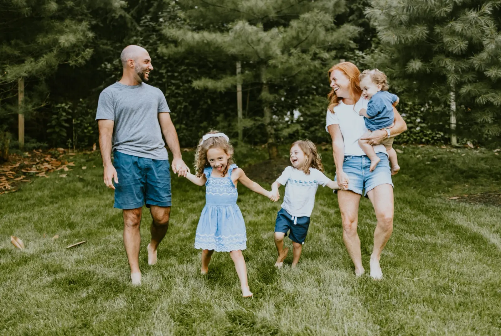 Kate's family walking hand in hand across the grass on a summer morning