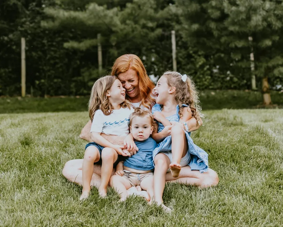 Kate laughing with her three kids on the grass